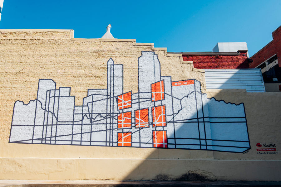 Mural featuring Raleigh's skyline in white and orange paint.