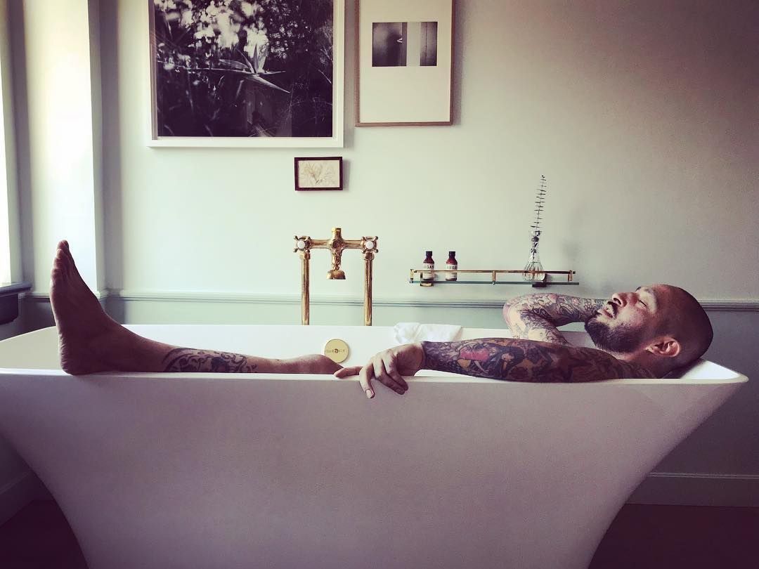 Man with tatoos in bathtub