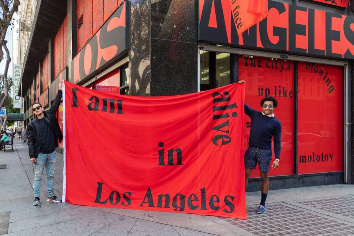 Men holding banner I am alive in LA