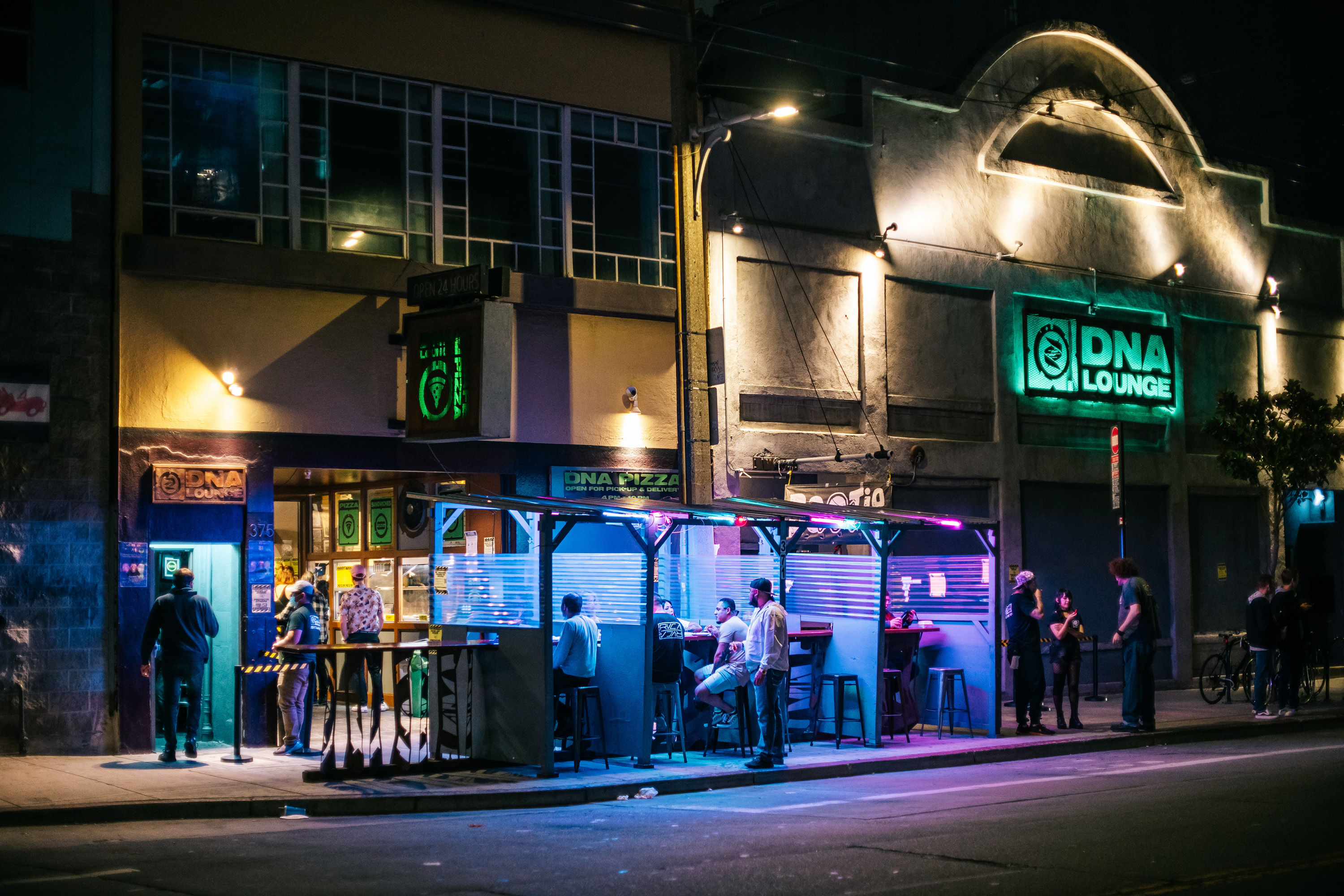 Picture of people in a parklet outside of DNA Lounge at night