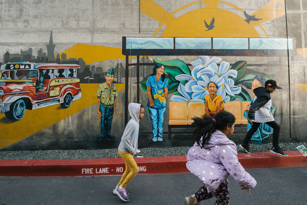Children running and playing in front of the mural