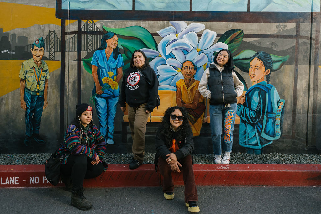 Artists posing in front of the Cece Carpio mural