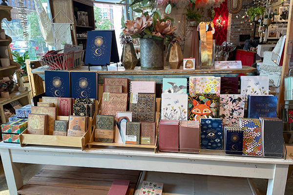 Various journals and notebooks with patterns on the covers are displayed on a wooden display