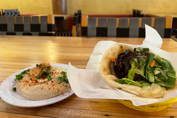 A photo of a lamb gyro and hummus on a table in a restaurant.