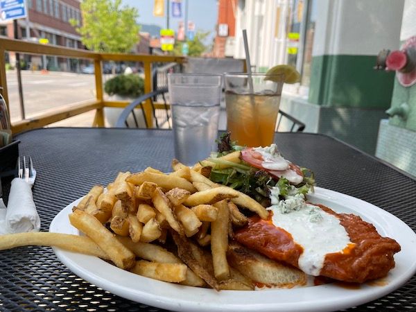 French fries, two drinks, and a buffalo chicken sandwich are on a table outside