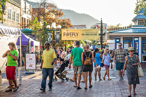 People walking on an outdoor mall with a banner in the back reading "Firefly Market" 