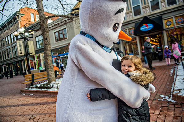 A girl hugs Freezie, downtown Boulder's snowman mascot, on the Pearl Street Mall