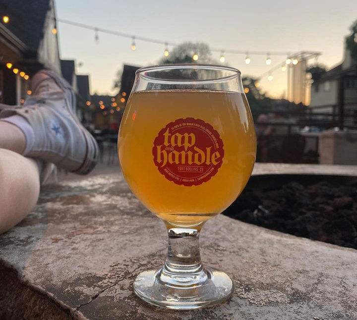 Beer on patio at dusk with lights at Tap and Handle