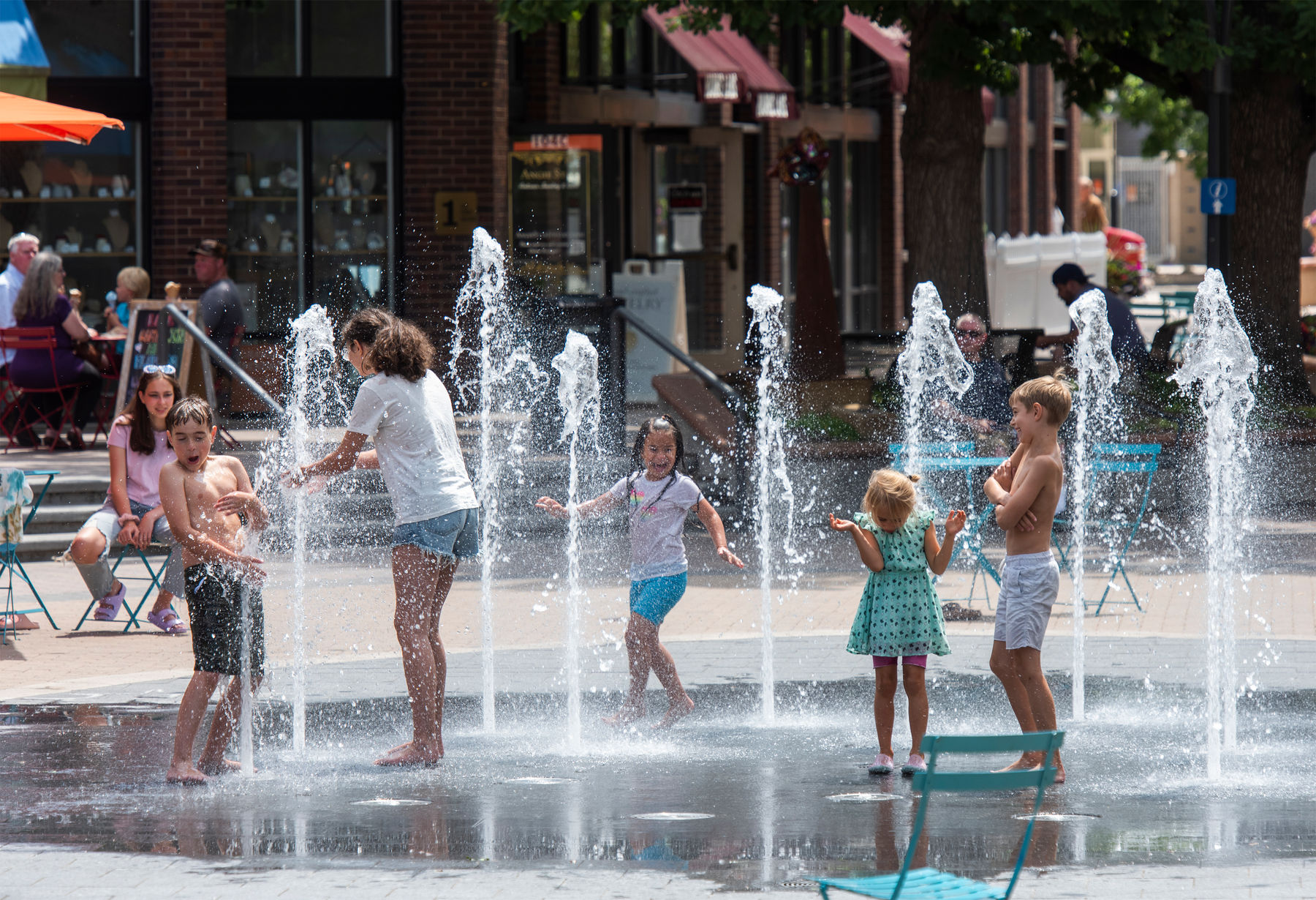 Kids cooling off playing in the splash pad during summer in Old Town Square