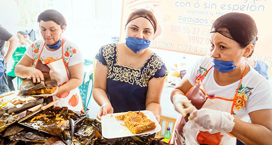 Tres mujeres sirven comida tradicional en un parque en Mérida, México