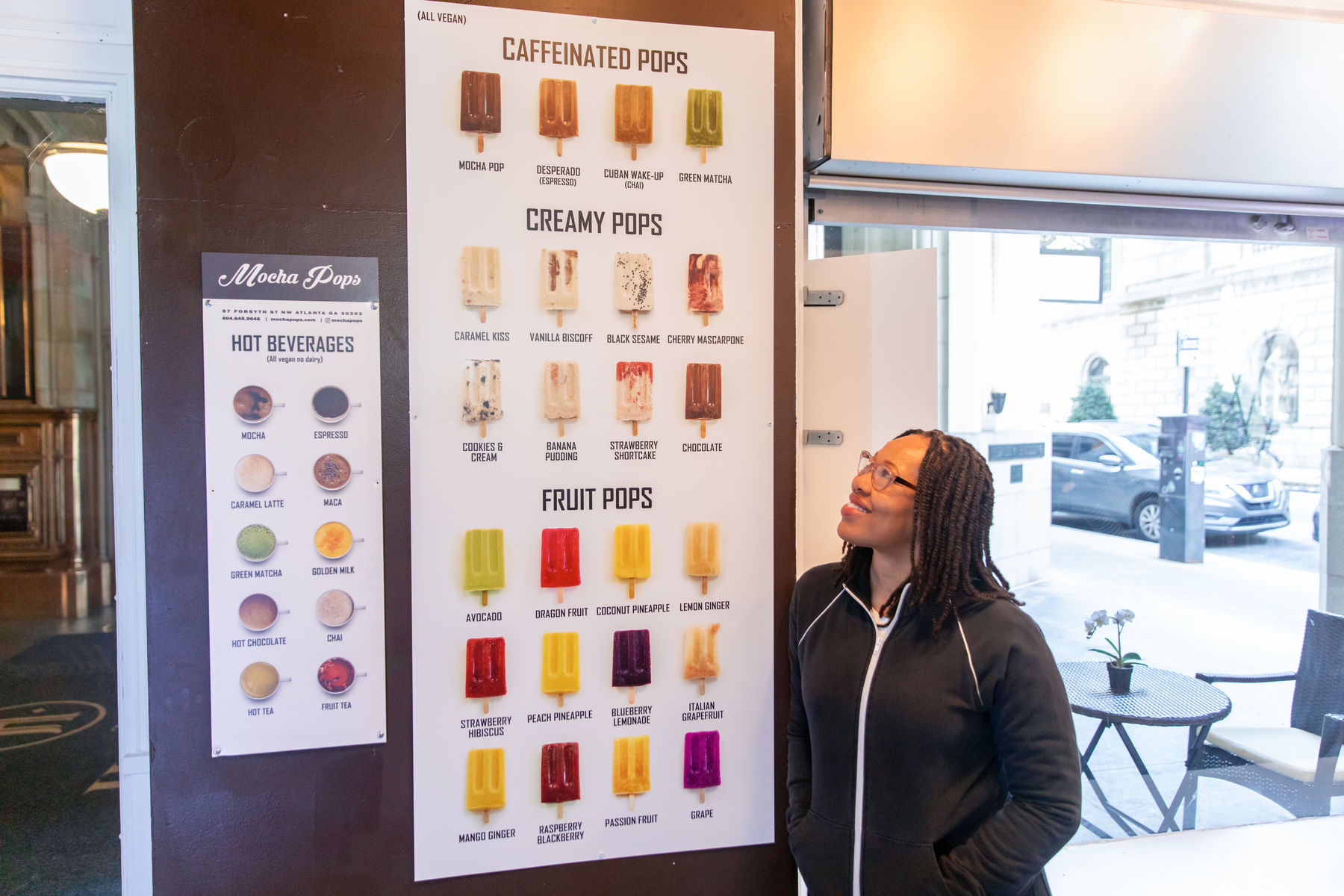owner Keisa Manning stands near a sign displaying all of the current flavors offered at her store mocha pops