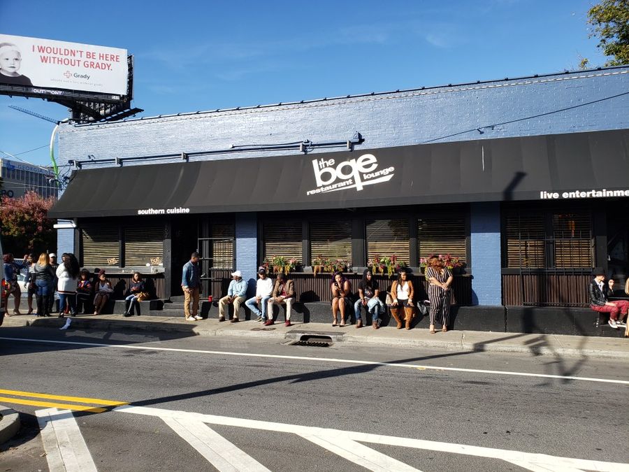 Image of building marquee of BQE Lounge with people sitting outside.