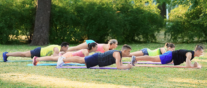 people doing yoga outdoors in a park