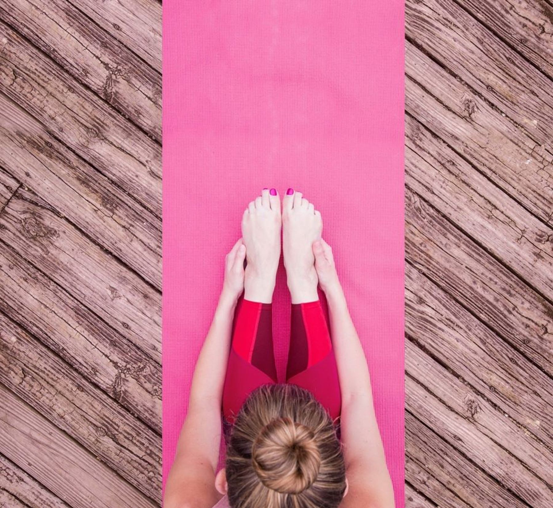 Woman doing yoga on pink mat