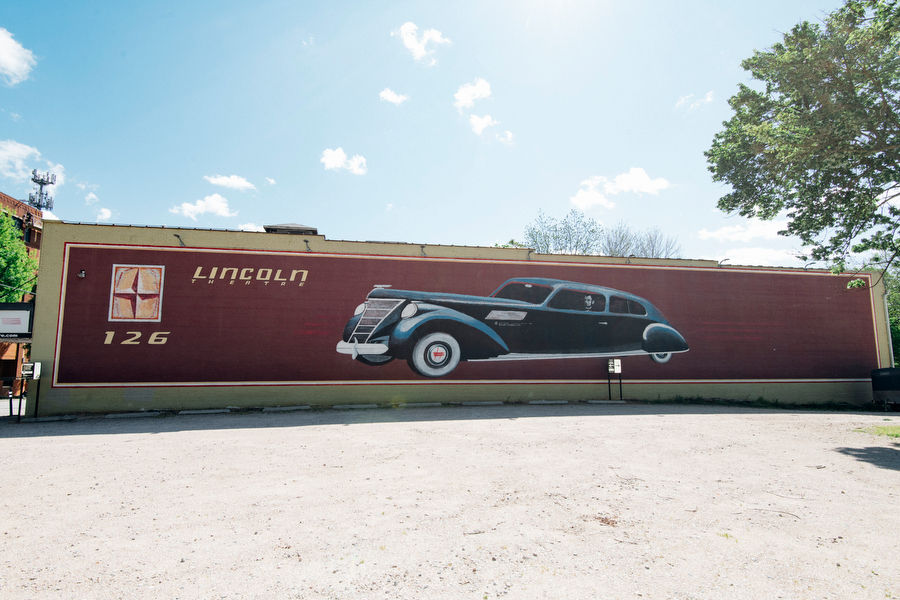 Mural on a brick wall depicting President Abraham Lincoln driving a 1950 Lincoln.