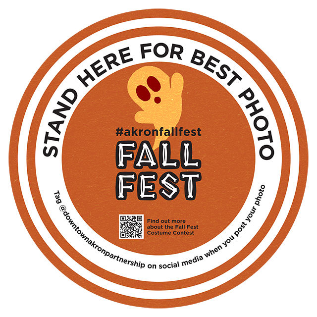 Graphic image that shows what one of the downtown Akron Fall Fest Photospots looks like (it's a circle with orange and white stripes and a ghost illustration)