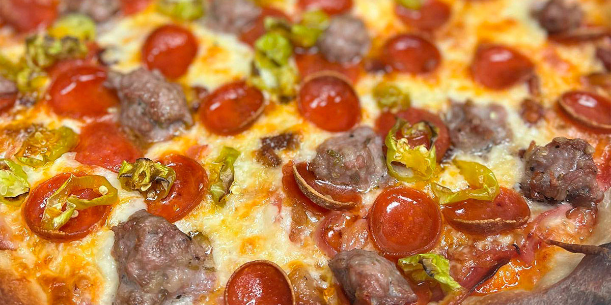 An up-close image of pepperoni, sausage, and pepper pizza from Totally Baked Pizza in Akron, Ohio
